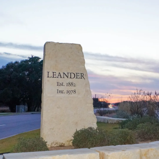 Stone monument sign at the entrance of Leander, TX at sunset, representing the city served by Just Call Sarah’s professional house cleaning services. This image is used on the Leander service area page to highlight local coverage. 