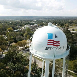 Aerial view of the Liberty Hill water tower surrounded by trees and residential homes. This image represents the local area served by Just Call Sarah’s professional house cleaning services in Liberty Hill, TX. 
