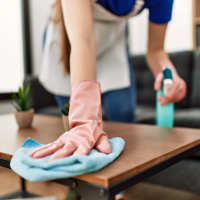 A person wearing pink gloves is cleaning a wooden table with a microfiber cloth and spray cleaner. This image represents our affordable cleaning service in Round Rock, TX, showcasing the detailed cleaning tasks we handle. Check out our blog, '5 Signs It’s Time to Hire a Professional Cleaning Service in Round Rock, TX,' for more tips on when to call the experts.