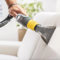 A close-up of a professional cleaner using a vacuum cleaner to deep clean upholstery. This image represents our maid service in Georgetown, TX, specializing in upholstery and furniture cleaning to keep your home spotless and fresh.
