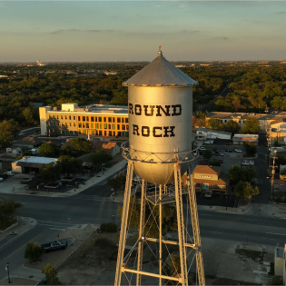 Aerial view of the historic Round Rock water tower at sunset, symbolizing the local area served by Just Call Sarah. This image is featured on the Round Rock, TX house cleaning service page to highlight local availability and trusted service. 