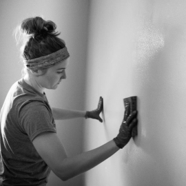 A professional house cleaner wearing gloves and holding cleaning supplies, ready for a deep clean in a home in Round Rock, TX. This image represents Just Call Sarah’s trusted house cleaning services in the local area.